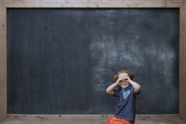 Junge vor einer Tafel stehend, der mit den Händen Gläser herstellt - ISF12190