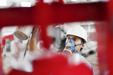 Nahaufnahme eines männlichen Fabrikarbeiters, der einen roten Kran in einer Werkshalle besprüht, China - ISF12211