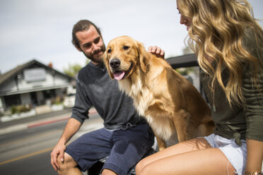 Young couple with dog sitting in back of jeep - ISF12224