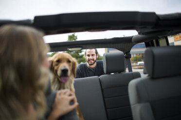 Young woman in jeep looking over her shoulder at dog and boyfriend - ISF12226