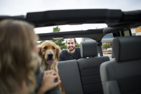 Junge Frau im Jeep schaut über ihre Schulter auf Hund und Freund - ISF12226