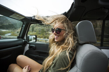 Young woman with windswept long blond hair on the road in jeep - ISF12229