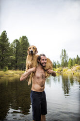 Junger Mann trägt nassen Hund über die Schultern im Fluss, Lake Tahoe, Nevada, USA - ISF12241