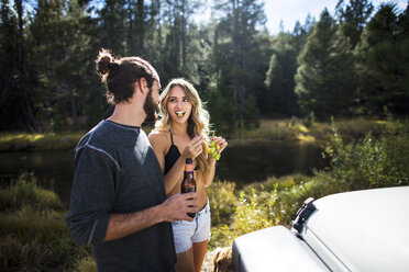 Young couple eating grapes on riverside, Lake Tahoe, Nevada, USA - ISF12248