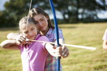 Mädchen lernt Bogenschießen von Schwester im Teenageralter - ISF12296