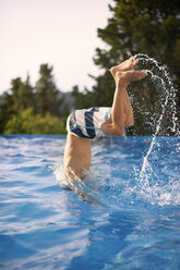 Upside down teenage boy diving into outdoor swimming pool - ISF12347