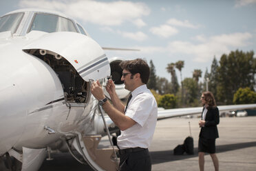 Männlicher Pilot bei der Kontrolle eines Privatjets am Flughafen - ISF12395