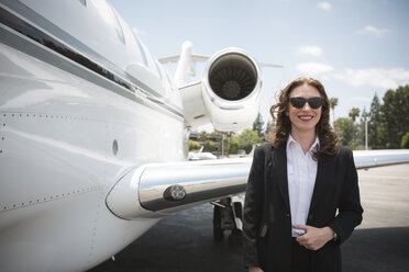 Porträt einer mittelgroßen Geschäftsfrau und eines Privatjets auf dem Flughafen - ISF12400