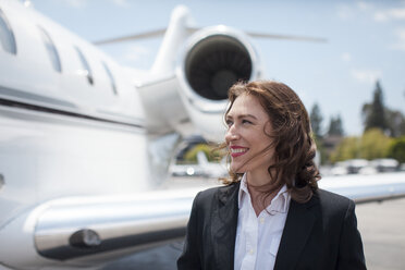 Mid adult female businesswoman and private jet at airport - ISF12402