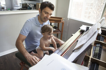 Baby boy sitting on fathers knee playing piano - ISF12488