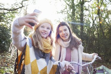 Teenager-Mädchen im Wald mit Smartphone, um lächelnd ein Selfie zu machen - ISF12538