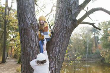 Jugendliches Mädchen am Fluss, das einem Freund beim Klettern auf einen Baum hilft - ISF12544