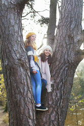 Teenage girls standing in tree looking away smiling - ISF12545