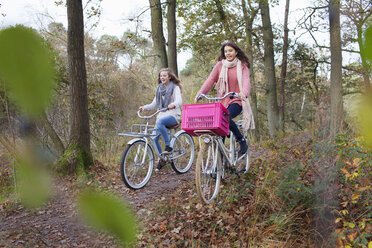 Teenager-Mädchen im Wald auf Fahrrädern mit rosa Kiste befestigt - ISF12557