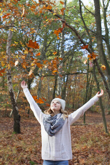 Teenager-Mädchen im Wald, die Arme erhoben, Herbstblätter werfend, lächelnd aufblickend - ISF12561