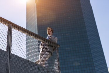 Niedriger Blickwinkel auf einen jungen Geschäftsmann, der auf einem Balkon in der Stadt New York mit seinem Smartphone plaudert, New York, USA - ISF12570
