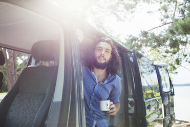 Junger Mann trinkt Kaffee im Van am See - ISF12594