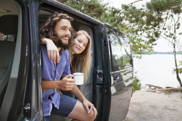 Young couple relaxing in van by lake - ISF12595