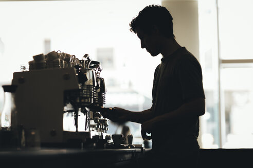 Silhouette eines Barista, der Kaffee in einer Kaffeebar zubereitet - OCAF00313