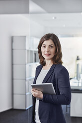 Portrait of smiling young businesswoman with tablet in office - RORF01258