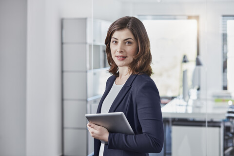 Porträt einer lächelnden jungen Geschäftsfrau mit Tablet im Büro, lizenzfreies Stockfoto