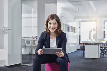 Portrait of smiling young businesswoman using tablet in office - RORF01264