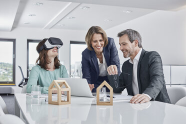 Business people having a meeting in office with VR glasses, laptop and architectural models - RORF01279