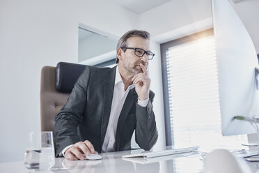 Geschäftsmann arbeitet am Schreibtisch im Büro - RORF01281