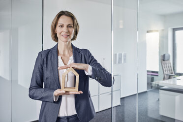 Portrait of businesswoman holding architectural model in office - RORF01286