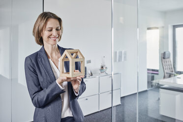 Smiling businesswoman looking at architectural model in office - RORF01290