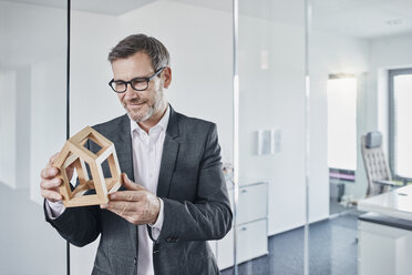 Smiling businessman looking at architectural model in office - RORF01291