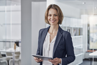 Porträt einer lächelnden Geschäftsfrau, die ein Tablet im Büro hält - RORF01307