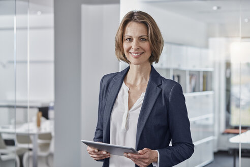 Portrait of smiling businesswoman holding tablet in office - RORF01307