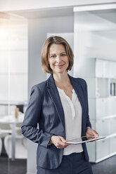 Porträt einer lächelnden Geschäftsfrau, die ein Tablet im Büro hält - RORF01308