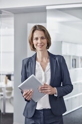 Portrait of smiling businesswoman holding tablet in office - RORF01309