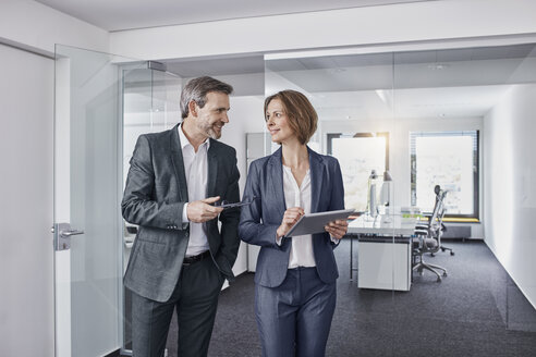 Smiling businessman and businesswoman using tablet in office together - RORF01313