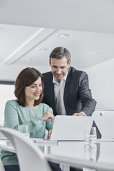 Businessman and businesswoman having a meeting in office with laptop - RORF01336