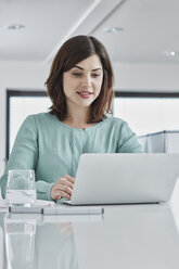 Young businesswoman using laptop at desk in office - RORF01340