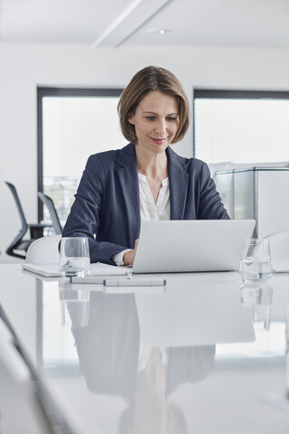 Geschäftsfrau mit Laptop am Schreibtisch im Büro, lizenzfreies Stockfoto