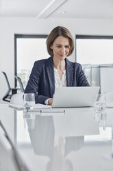 Businesswoman using laptop at desk in office - RORF01346