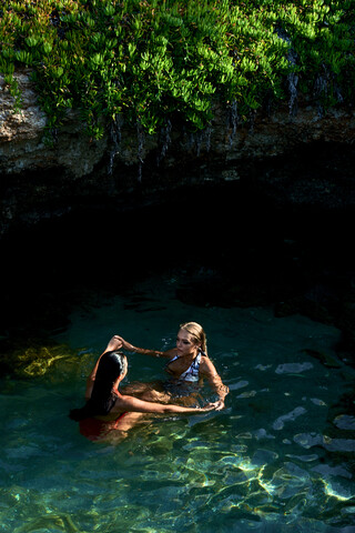 Junge Frau schwimmt in der Lagune mit ihrer besten Freundin, lizenzfreies Stockfoto