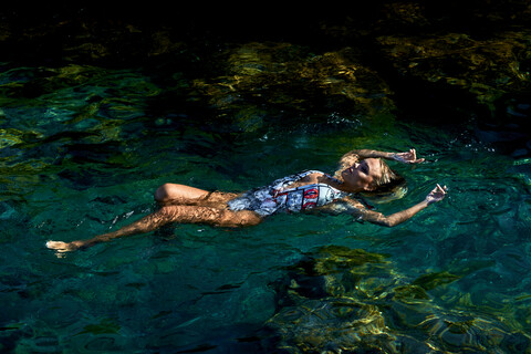 Junge Frau schwimmt auf dem Wasser in einer Lagune, lizenzfreies Stockfoto