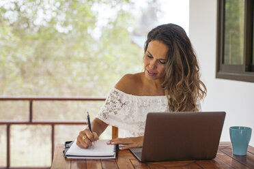 Woman using laptop at home - MOMF00446