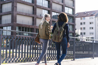 Freunde gehen auf einer Brücke spazieren, unterhalten sich, haben Spaß, Rückansicht - UUF14155