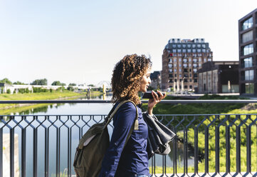 Young businesswoman walking on bridge, talking on the phone - UUF14156