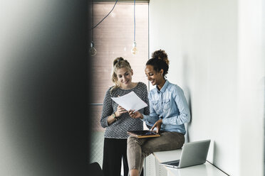 Young women working together in office, reading documents - UUF14190