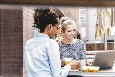 Young colleagues sitting outdoors, working together, having lunch - UUF14192