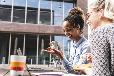 Young colleagues sitting outdoors, working together, having lunch - UUF14197