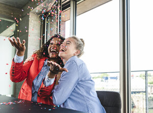 Young busniesswomen celebrating success, throwing confetti - UUF14240