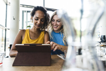 Beste Freunde treffen sich in einem Café, unterhalten sich und tauschen Neuigkeiten aus, benutzen ein digitales Tablet - UUF14242